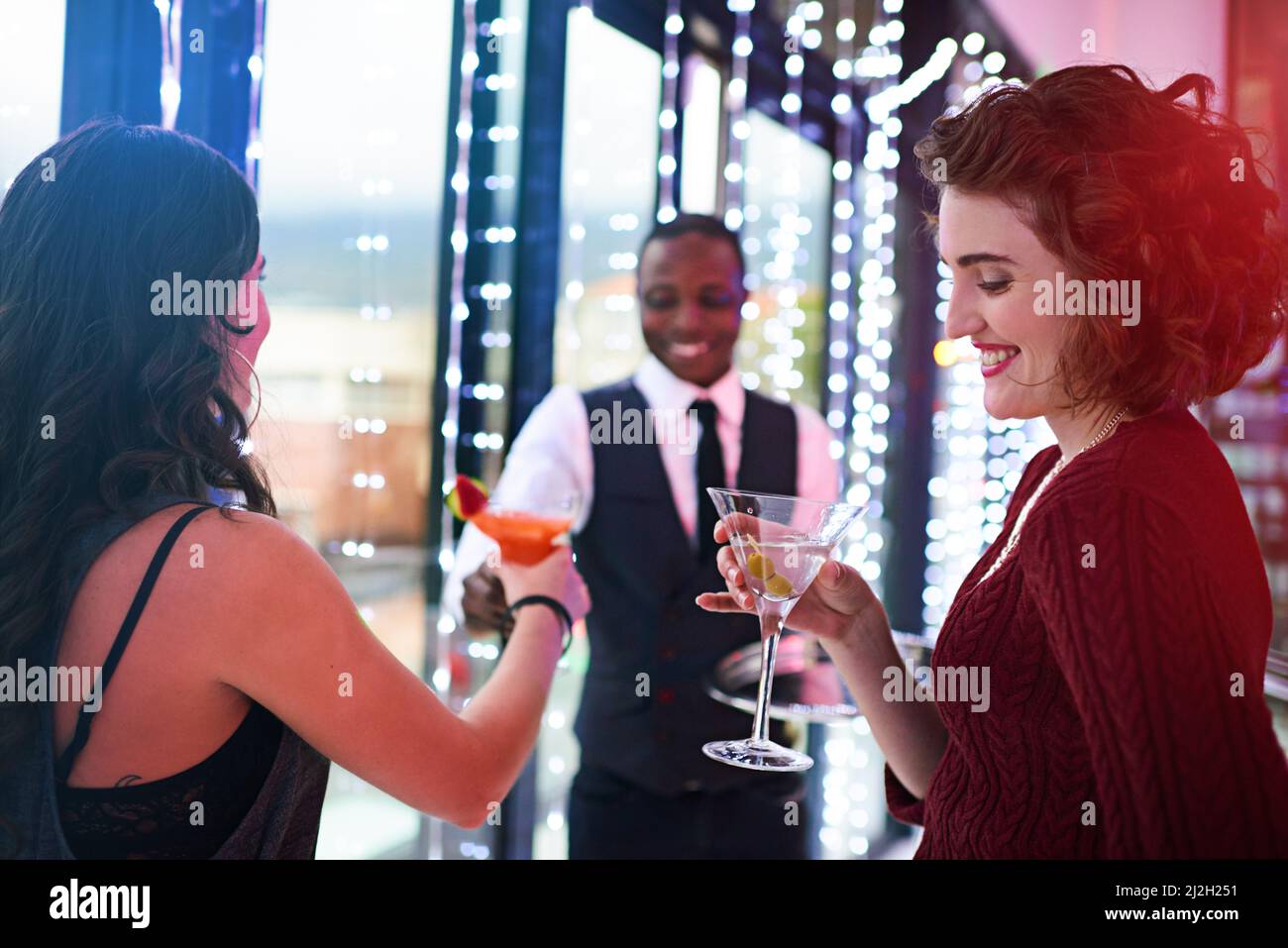 Il divertimento è appena iniziato. Shot di cameriere che serve due cocktail donne a una festa. Foto Stock