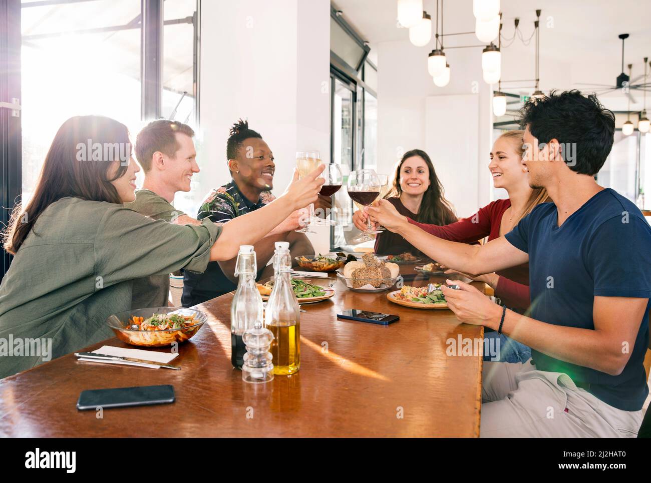 Amici sorridenti che tostano con vino al ristorante Foto Stock