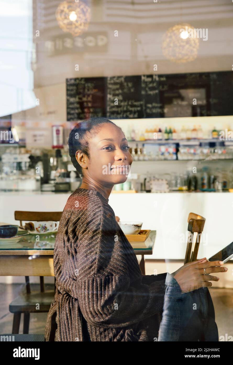 Donna sorridente con tablet digitale in un bar Foto Stock