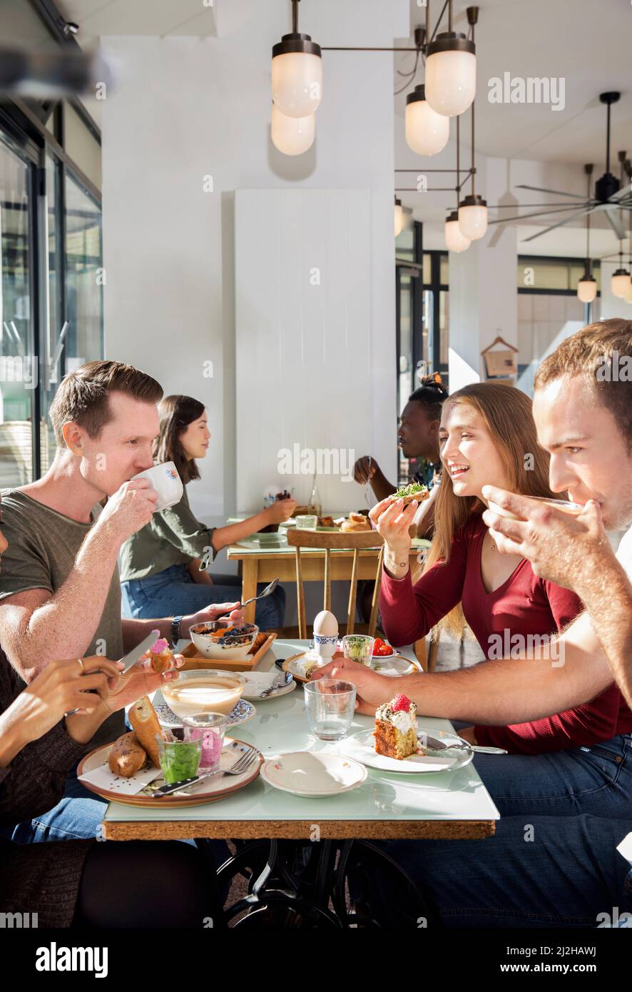 Gruppo di amici sorridenti che gustano la colazione al ristorante Foto Stock