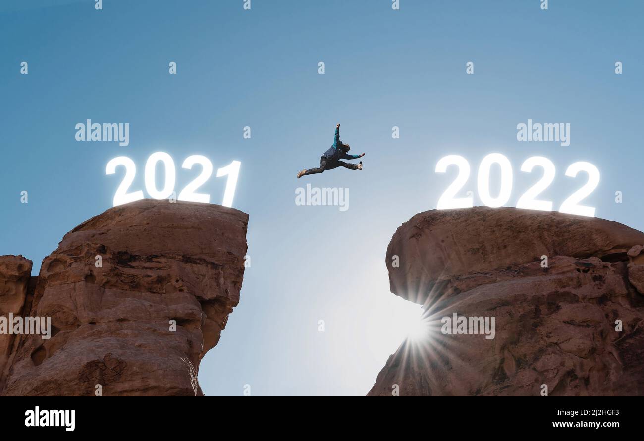 2022 nuovo anno concetto, silhouette un uomo che salta dall'anno 2021 al 2022 Foto Stock