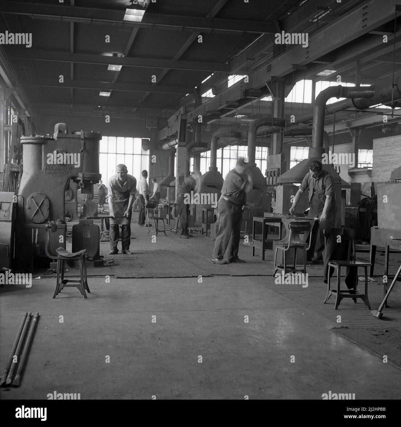 1950s, storico, negozio di un'officina di forgiatura, lavoratori maschi che formano e modellano metalli utilizzando le attrezzature del giorno per martellare, pressare o rotolare il metallo, Abbey Works Steel Complex, Port Talbot, Galles, Regno Unito. Foto Stock