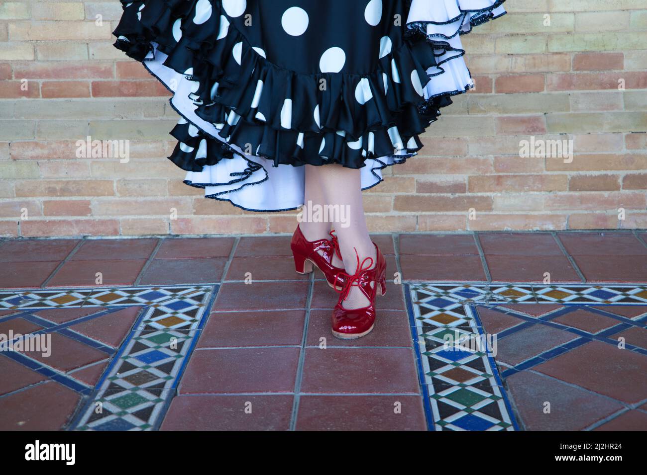 Un primo piano di scarpe da ballerino di flamenco con bruna ispanica contro il muro di mattoni marroni a Siviglia, Spagna Foto Stock