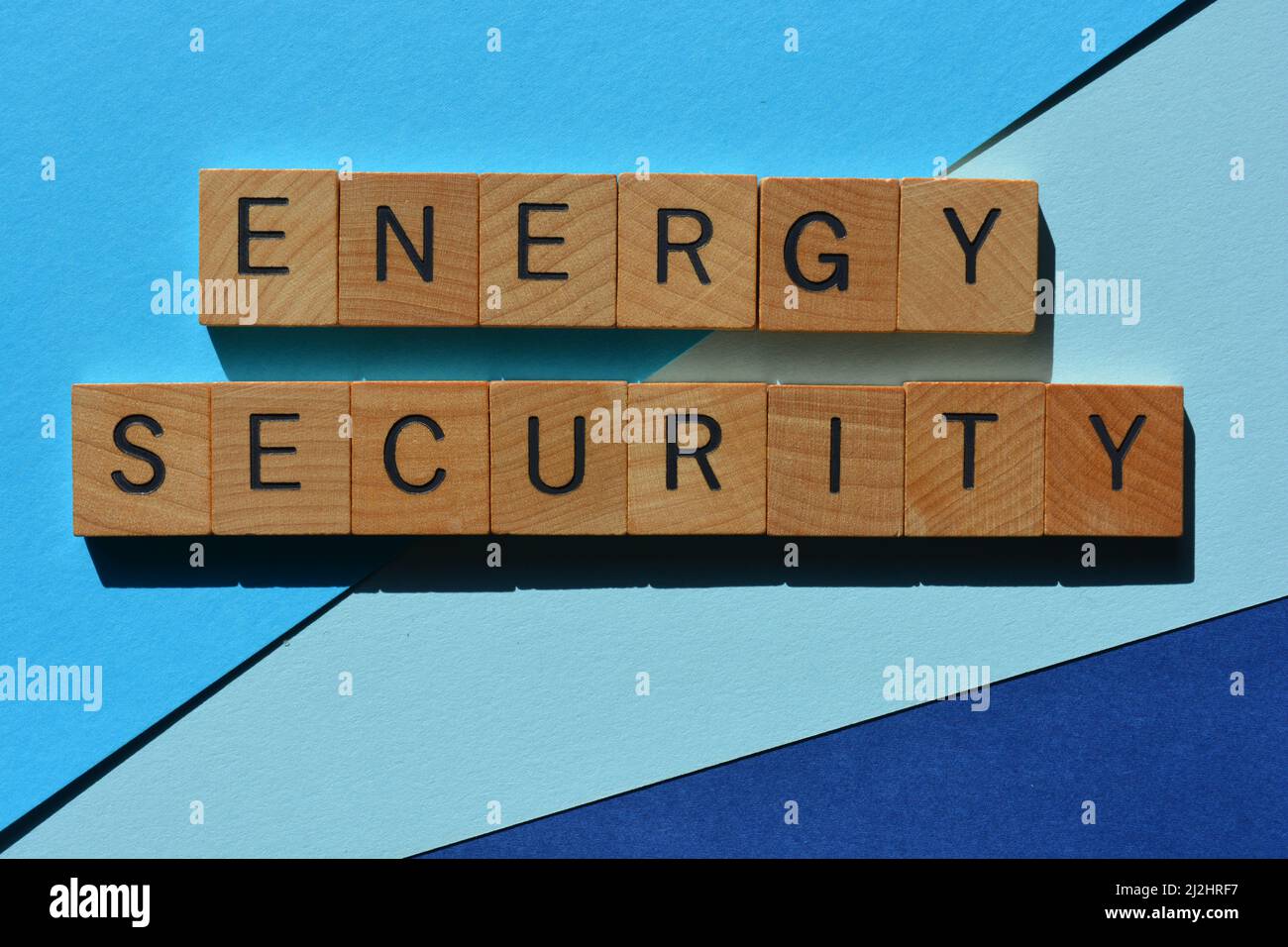 Energy Security, parole in lettere di legno isolate su sfondo blu Foto Stock