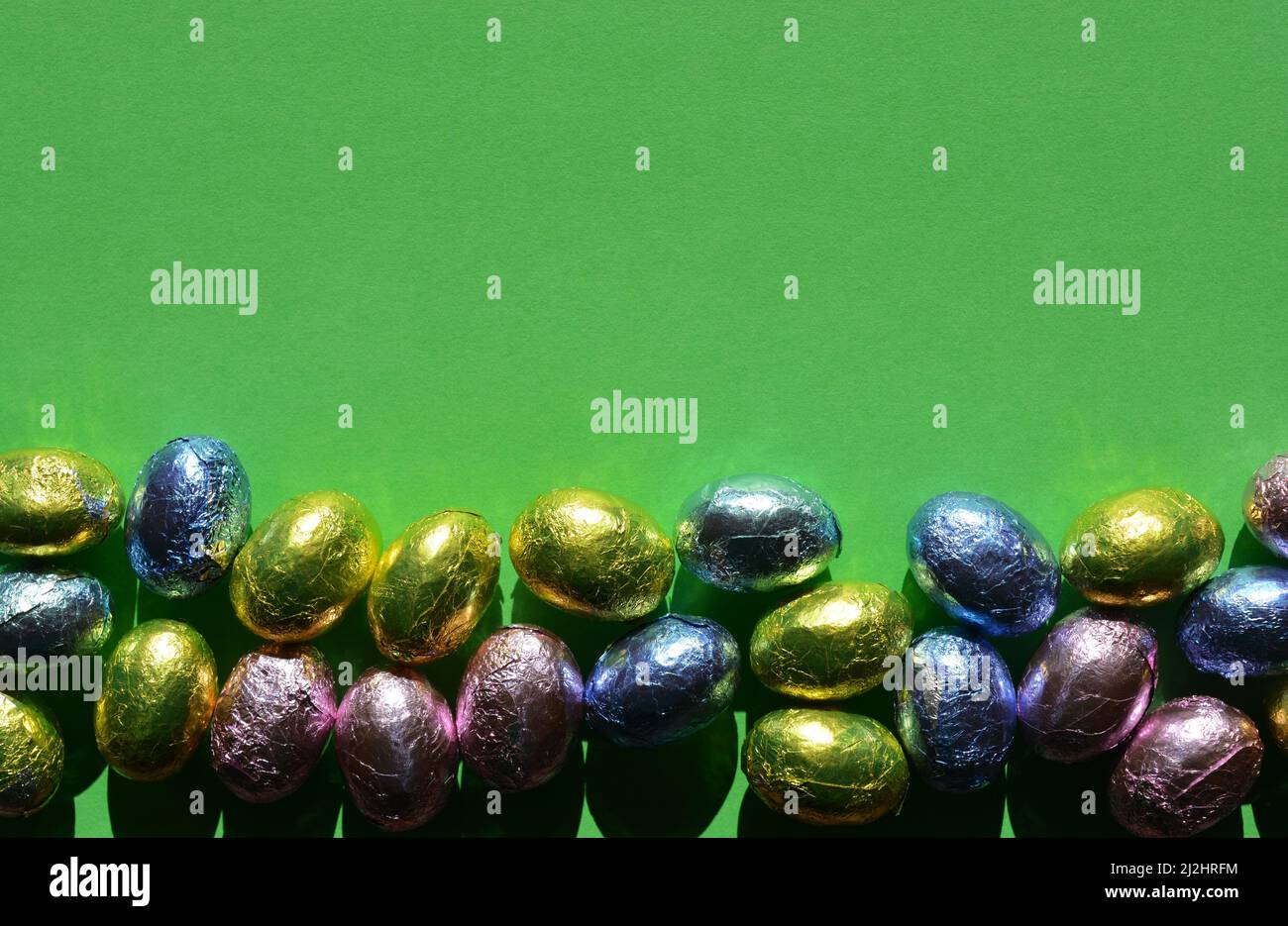 Foglia di cioccolato avvolto uova di Pasqua isolato su sfondo verde chiaro con spazio copia Foto Stock