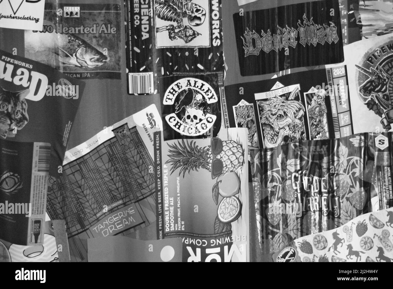 Un mucchio di adesivi che rappresentano la cultura pop trovato su un muro nel centro di Chicago in scala di grigi in bianco e nero. Foto Stock