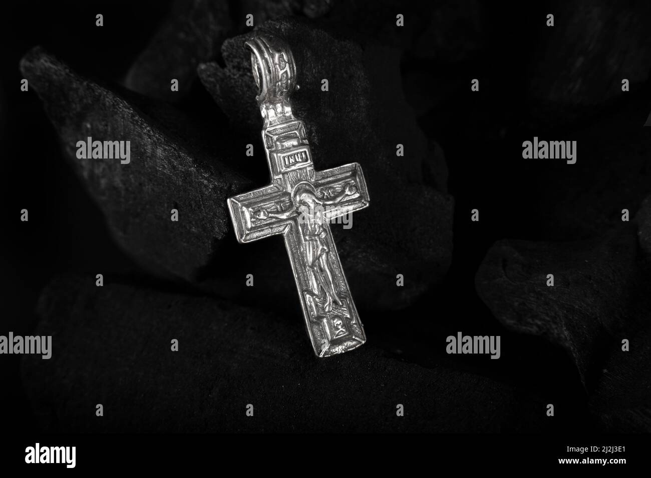 Collana crocefisso in argento su pezzi di carbone. Foto Stock