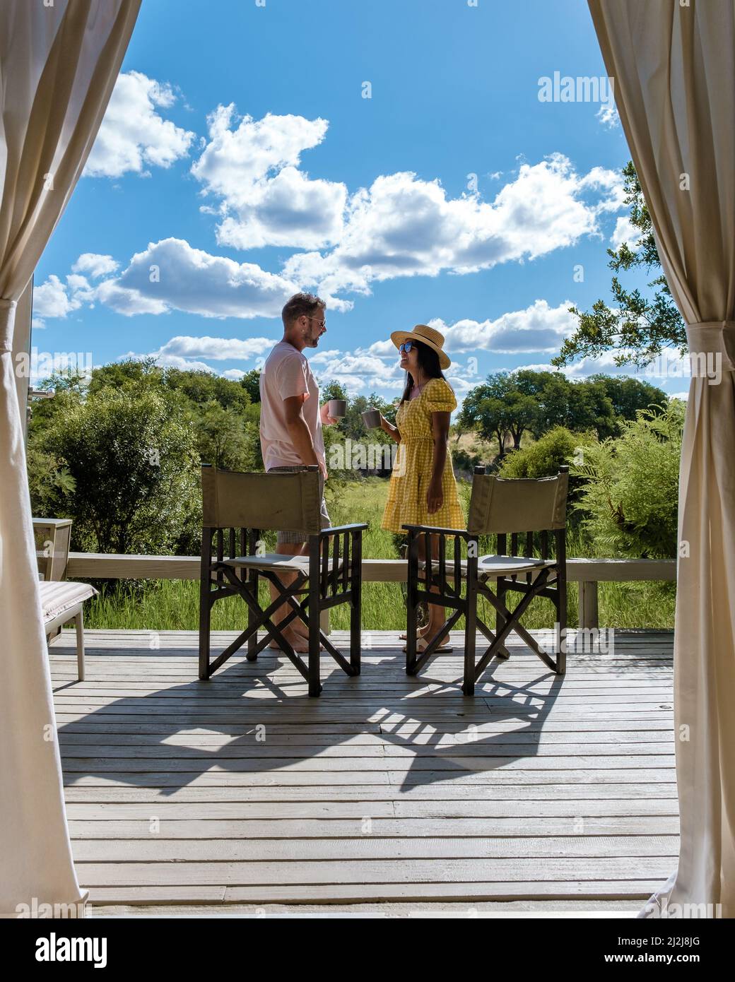 Coppia uomini e donne di fronte a una tenda safari in safari di lusso, Sudafrica, un rifugio safari di lusso nel bush di una riserva di gioco Foto Stock