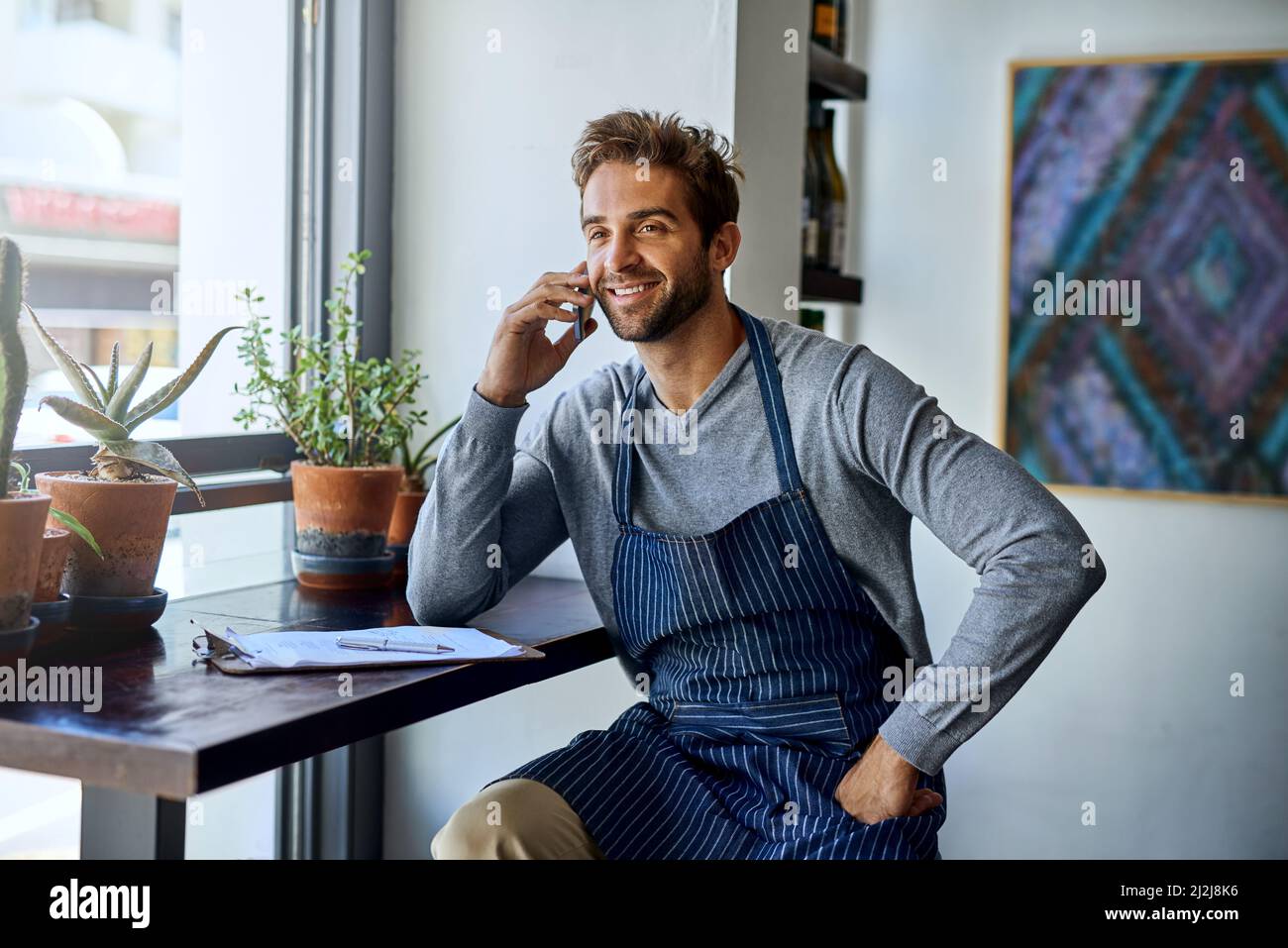 Certo, siamo in grado di realizzare. Scatto corto di un bel barista giovane che prende una chiamata mentre lavora nel suo bar. Foto Stock