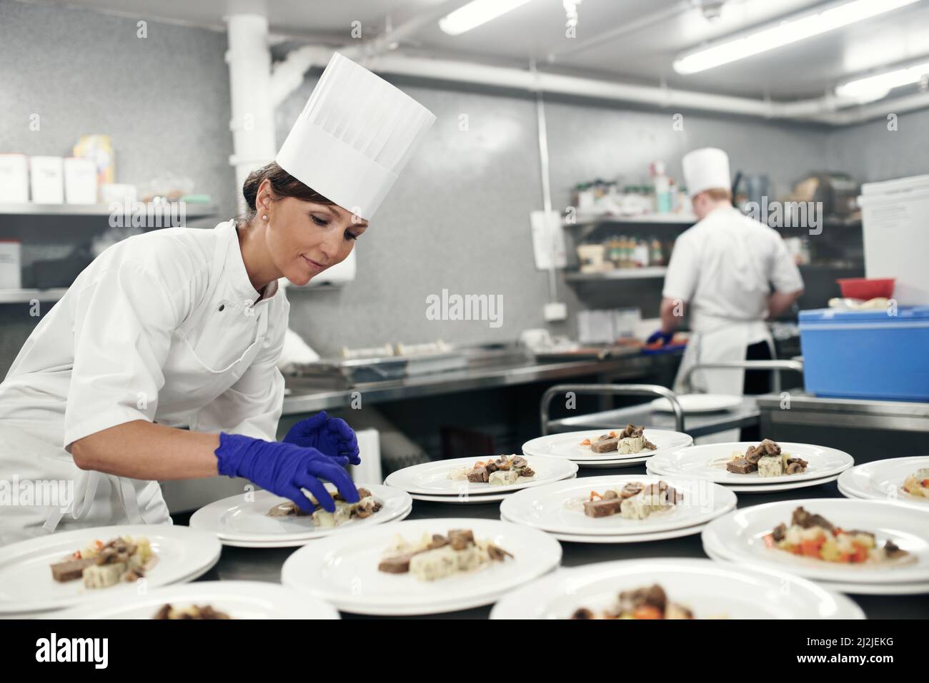 Fare la cena in un capolavoro. Shot di uno chef piatto cibo per un servizio pasti in una cucina professionale. Foto Stock