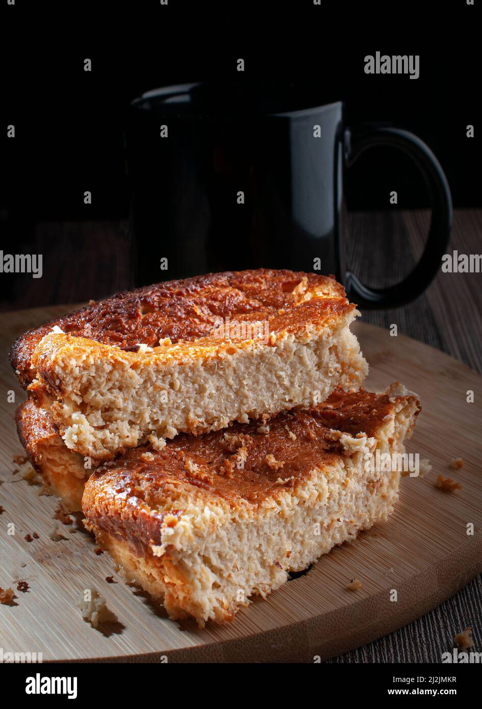 Pezzi fatti in casa di torta di mais su un bordo di taglio di legno rotondo con uno sfondo nero Foto Stock