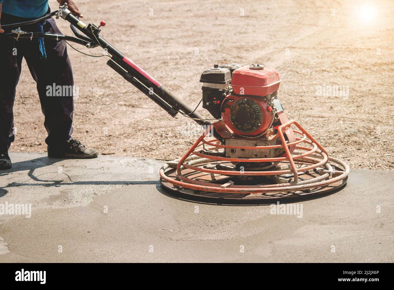 Lucidatura pavimenti in calcestruzzo, l'operatore edile produce la Malta cementizia e rifinisce il calcestruzzo bagnato con un attrezzo speciale. Lame flottanti. Per levigare e lucidare Foto Stock