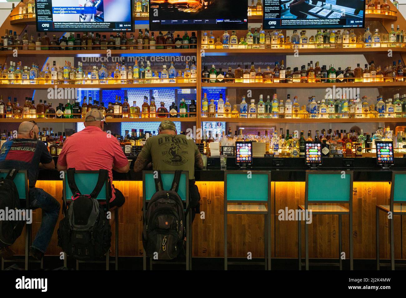 Tre uomini seduti in un bar con zaini all'aeroporto intercontinentale George Bush, Texas, Stati Uniti. Foto Stock