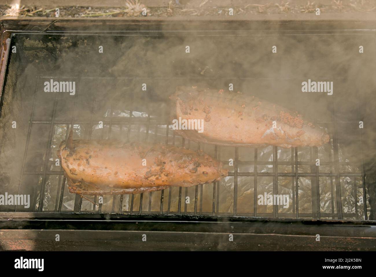 Sgombro di pesce in una marinata su una griglia in una casa di affumicatura. Il processo di cottura dello sgombro affumicato caldo. Foto Stock