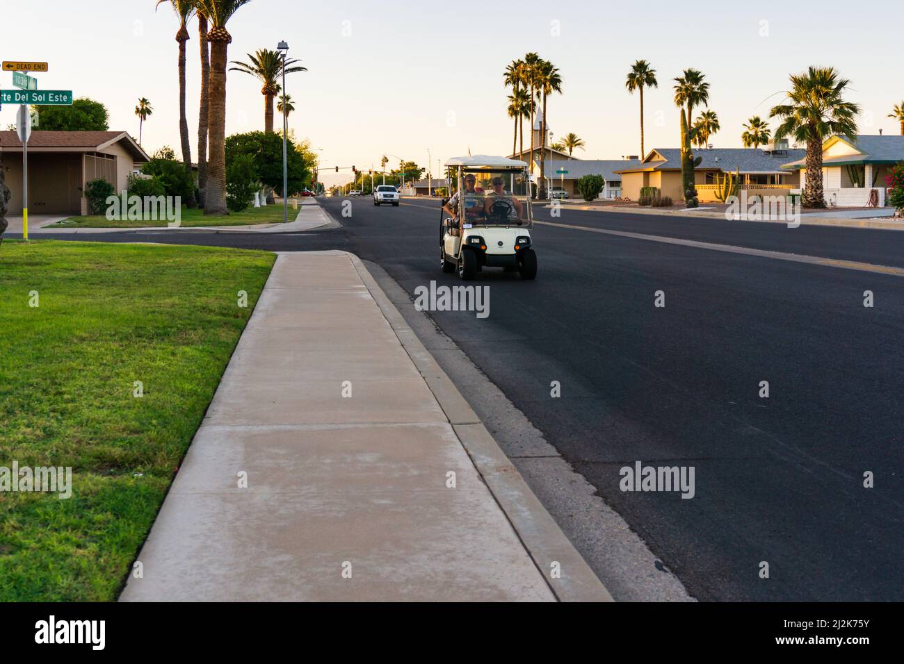 Vecchia coppia che guida un golf cart su una grande strada a Sun City, Arizona, U.S.A. Foto Stock