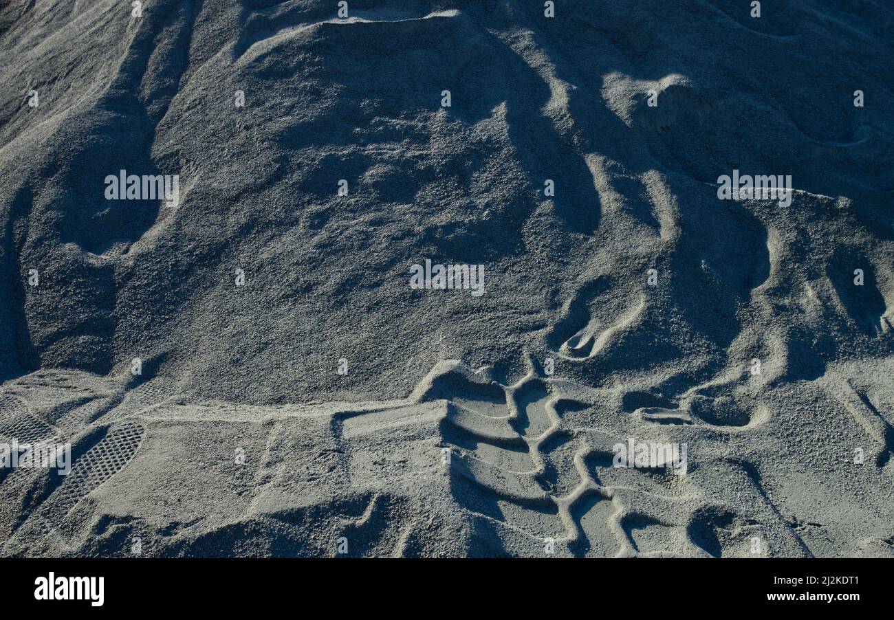 tracce di impronte delle scarpe e segni di scorrimento in sabbia grigia Foto Stock