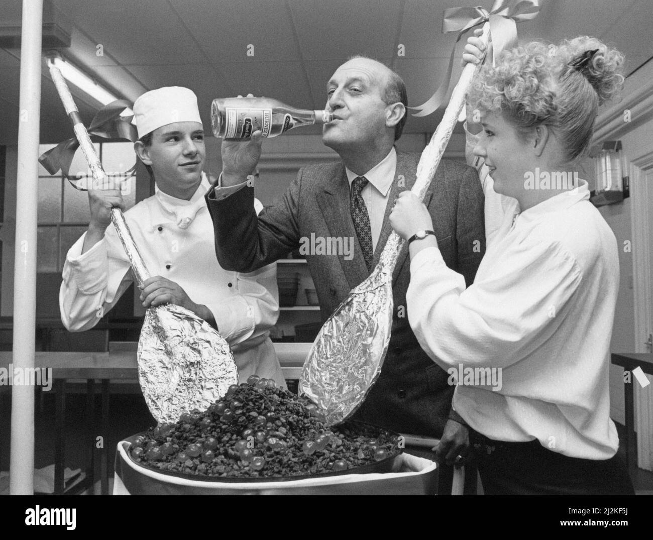 Sir John Hall, sviluppatore di proprietà (cavaliere 1991) e presidente di vita ed ex presidente del Newcastle United Football Club (1992-1997), nella foto di Wynyard Hall Estate, County Durham, 16th novembre 1988. La nostra foto mostra ... Trainee Commiss chef Richard Kirton 18 e Trainee fronte di casa Claire Marron 17, mix un gigante di Natale pud, come John Hall prova il brandy da utilizzare. Egli godrà di un buon gusto in una speciale cena della vigilia di Natale con 50 familiari e amici vicini. Foto Stock