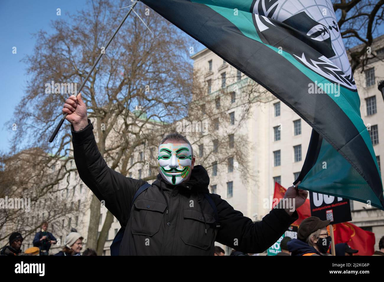 Londra, Regno Unito. 2 aprile 2022. Un uomo che indossa una maschera ondeggia una bandiera del gruppo hacktivist Anonymous fuori Downing Street dove la gente si è riunita per protestare contro il costo crescente di vivere nel paese. Credit: Kiki Streitberger/Alamy Live News Foto Stock