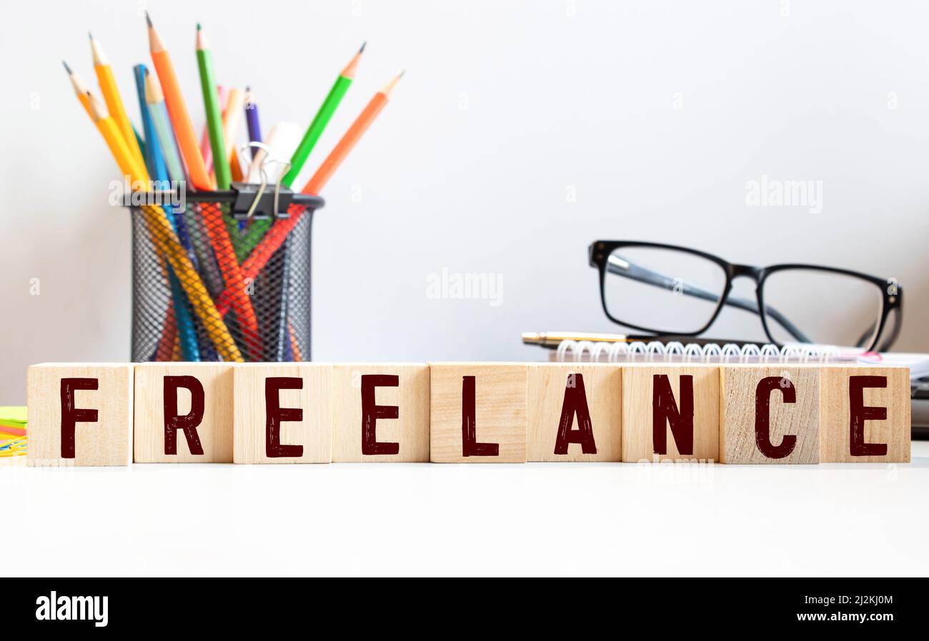 Parola FREELANCE su cubi di legno su sfondo bianco lucido. Foto Stock