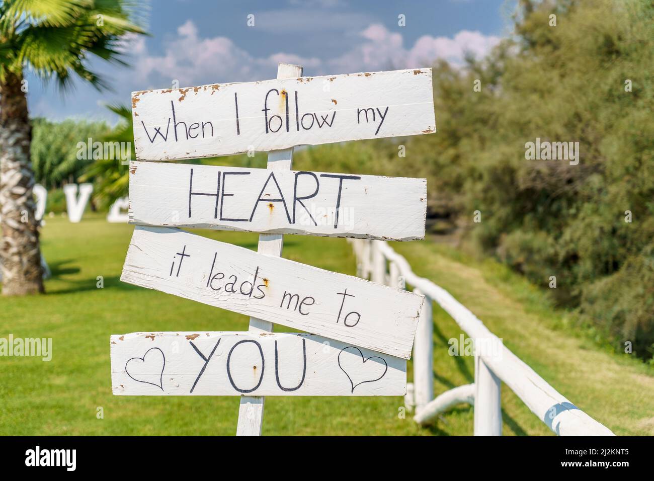 Quando seguo il mio cuore, mi porta a te, romantico amore scritta su tavole di legno bianco in un prato verde. Foto Stock