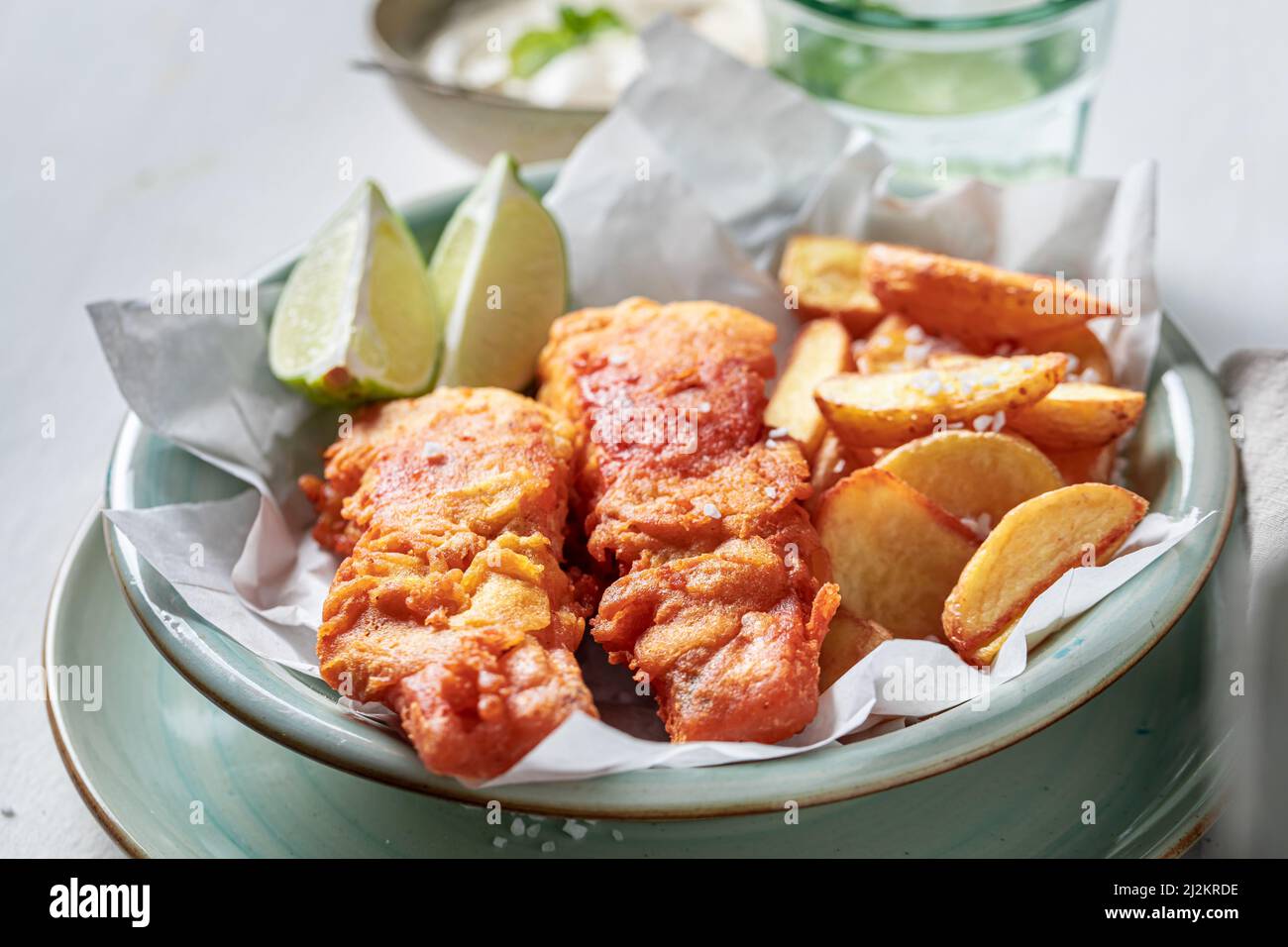 Pesce arrosto e patatine servite con lime e sale. Pesce classico e patatine servite in carta. Foto Stock