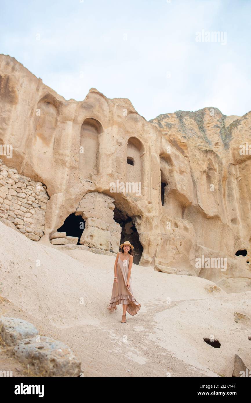 Giovane donna sullo sfondo di antiche formazioni rupestri in Cappadocia, Turchia. Il Monastero è uno dei più grandi edifici religiosi. Foto Stock