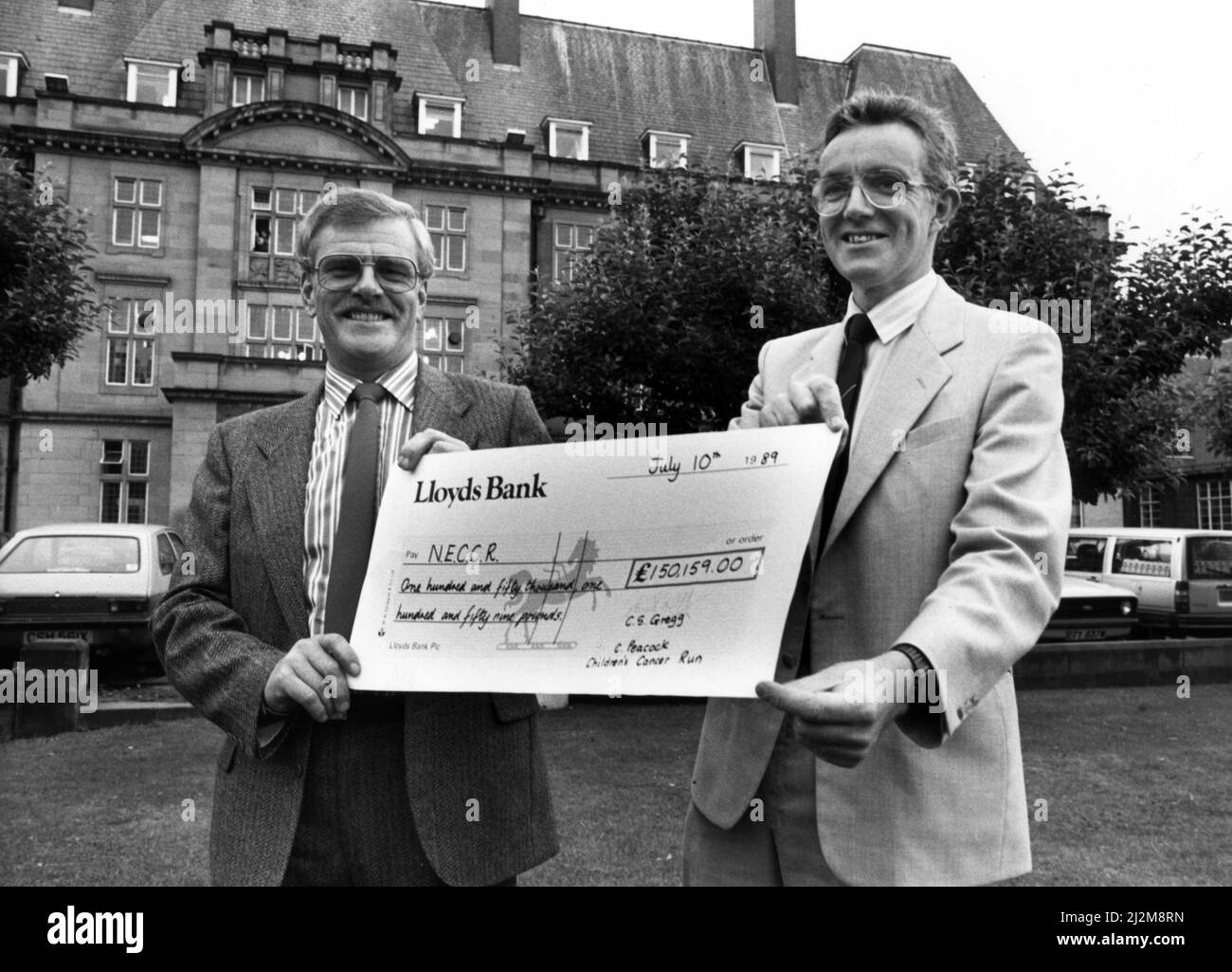 Un assegno per più di £150.000 raccolti da 10.000 partecipanti al Child Cancer Run, sponsorizzato da Greggs The Bakers, è stato presentato all'unità per il cancro dei bambini a Newcastle RVI. Colin Gregg (a sinistra) presenta l'assegno al dottor Alan Craft. 11th luglio 1989. Foto Stock
