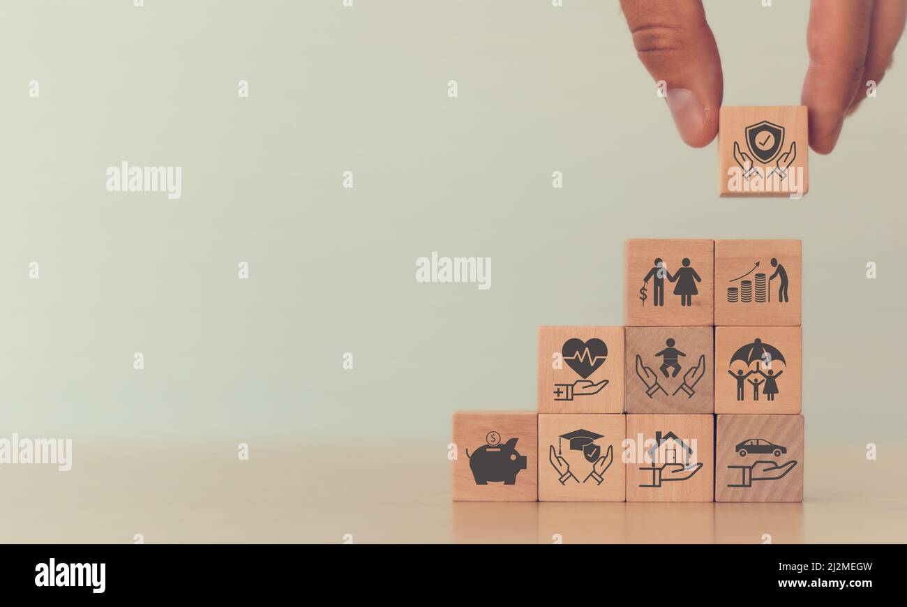 Concetto di assicurazione. Mano mettendo il cubo di legno con assicurazione e icona di assicurazione in piedi con finanze, istruzione, auto, immobiliare e proprietà, h Foto Stock