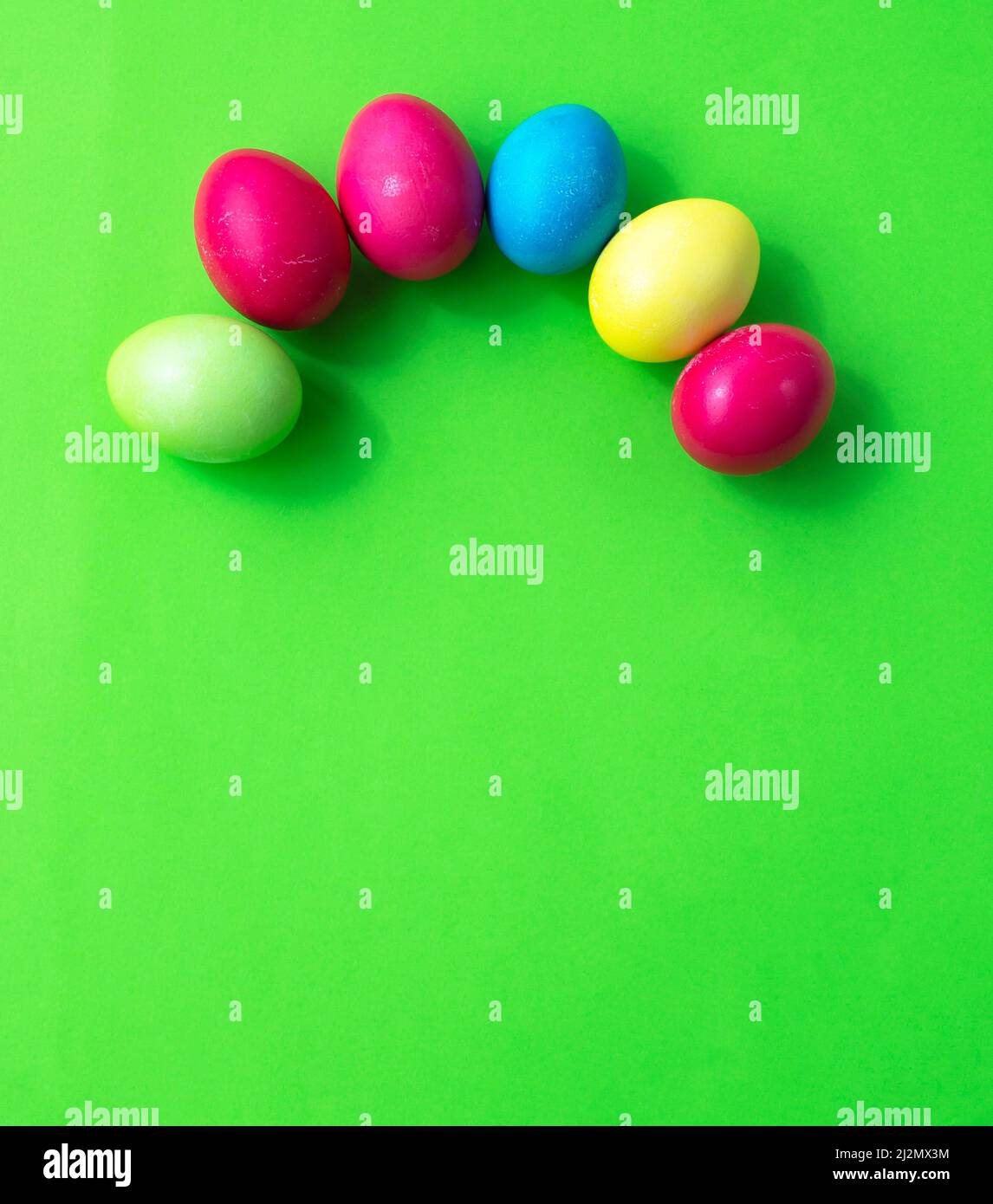 Le uova multicolore sono disposte in un arco su sfondo verde. Arcobaleno di Pasqua. Cartolina. Congratulazioni. Invito. Foto Stock