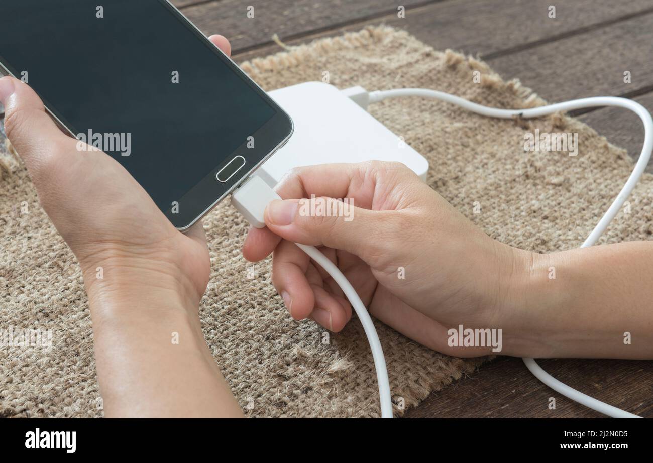 La donna sono collegato il cavo di ricarica per lo smartphone mediante la batteria esterna. Foto Stock