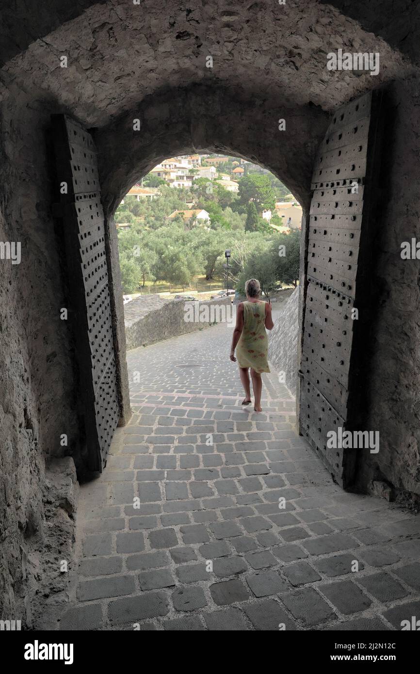 Donna che cammina attraverso la vecchia porta costellata di chiodi all'ingresso del castello di Ulcinj, Montenegro Foto Stock