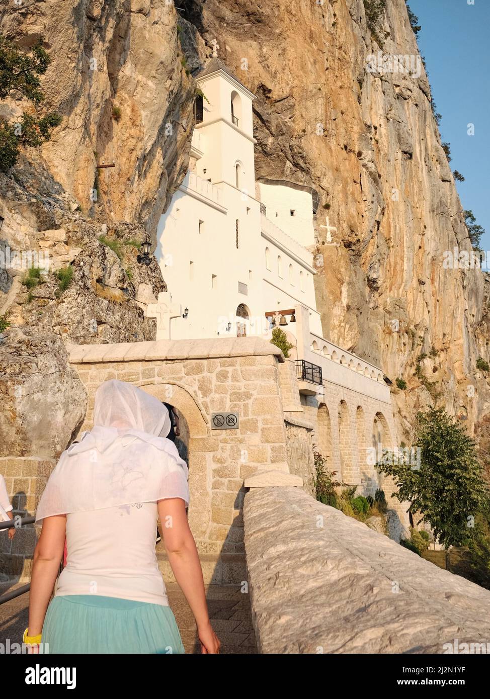 Monastero di Ostrog, donna pellegrina con velo sta andando alla chiesa grotta superiore - Montenegro Foto Stock
