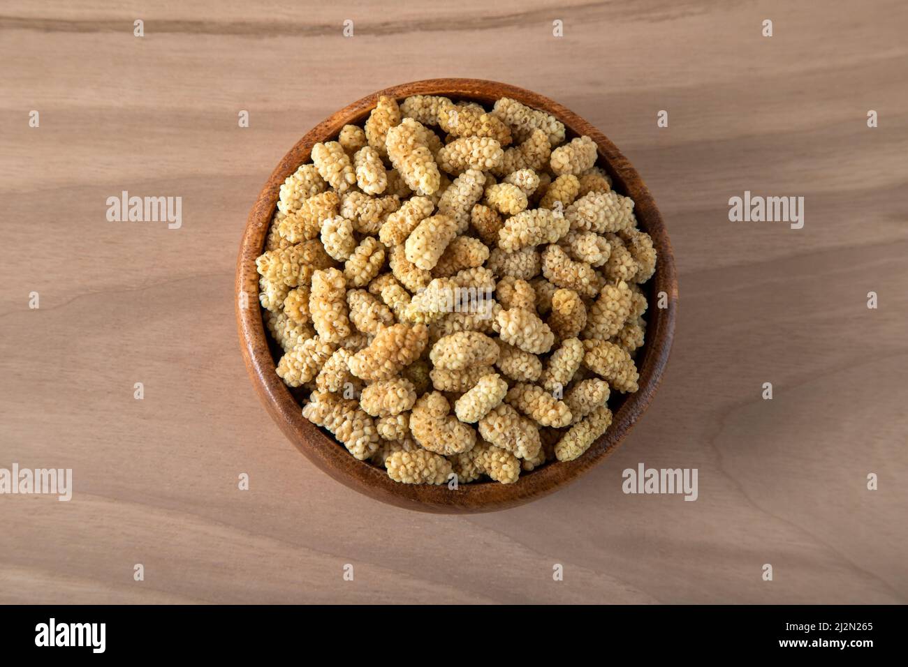 Ciotola piena di gelso secco su sfondo di legno Foto Stock