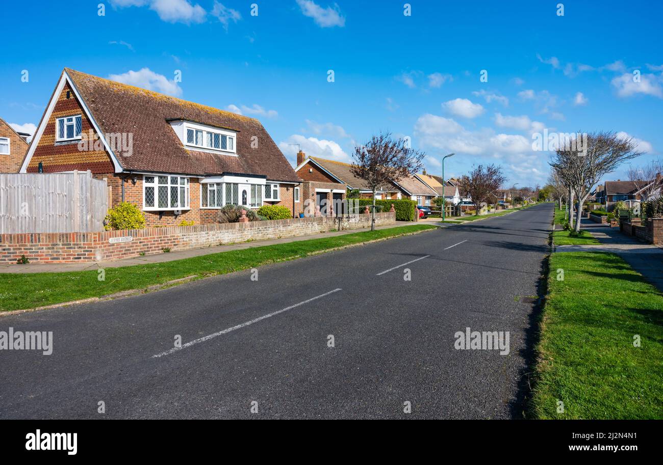 Strada residenziale lunga e diritta o strada senza auto di altri veicoli parcheggiati a Rustington, West Sussex, Inghilterra, Regno Unito. Strada vuota senza auto. Foto Stock