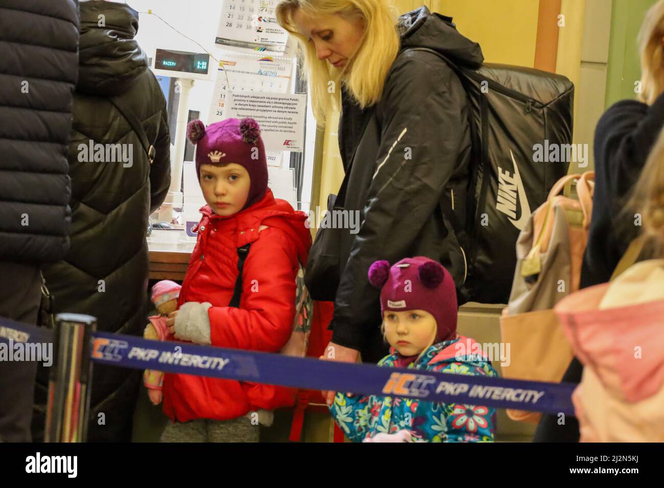 Przemysl, Polonia. 2nd Apr 2022. Bambino rifugiato ucraino in linea con la sua famiglia che acquista i biglietti. Lei e la sua sorella più anziana dietro di lei, indossano gli auricolari Topolino e ha un Topolino sul suo zaino (Credit Image: © Amy Katz/ZUMA Press Wire) Foto Stock