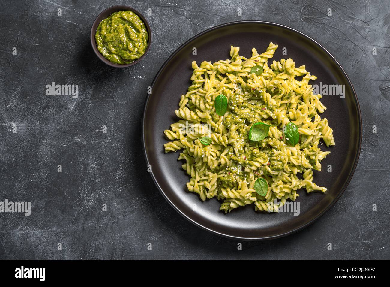 Pasta con salsa di pesto, foglie di basilico fresco e semi di sesamo. Foto Stock