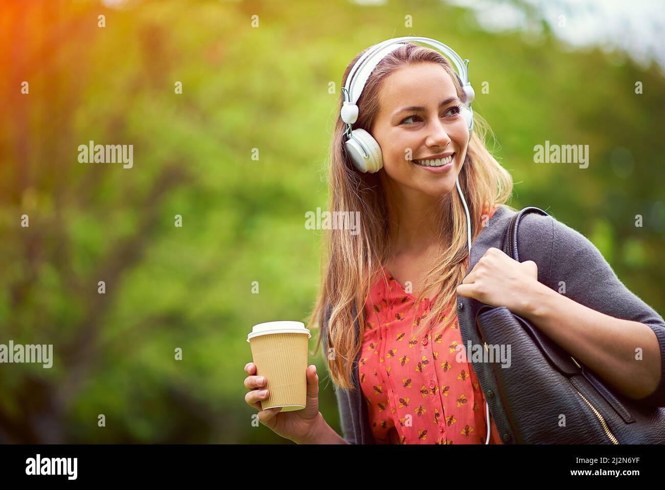 Porta con te musica e caffè. Scatto di una giovane donna che ascolta musica mentre si fa un caffè in movimento. Foto Stock