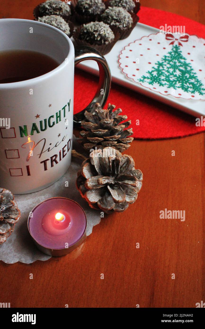 Palle dolci di cioccolato di Natale, alberi e cono di pino vicino alla tazza di tè Foto Stock