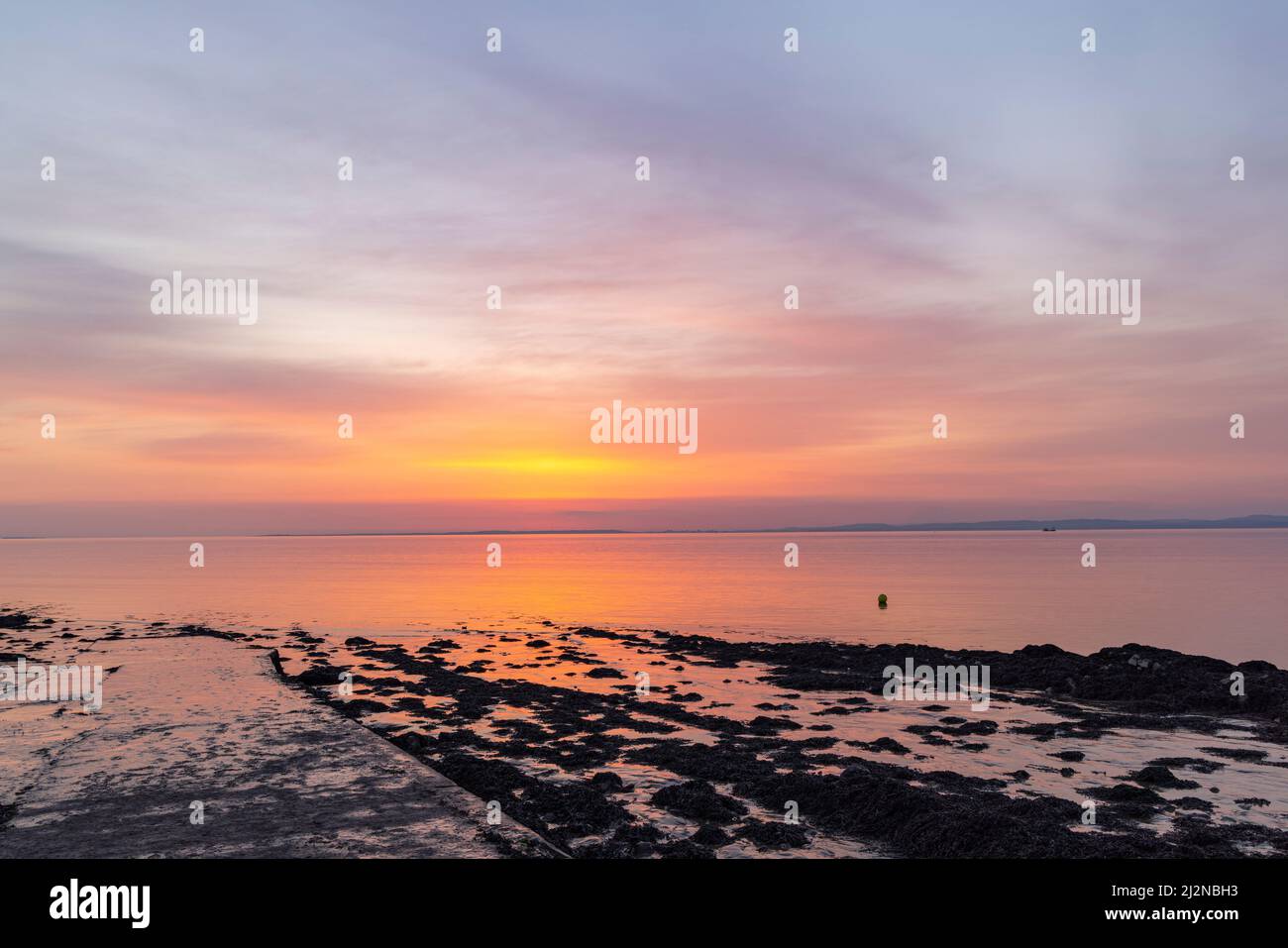 Un leggero bagliore di pinkish che si riflette su un mare calmo Foto Stock
