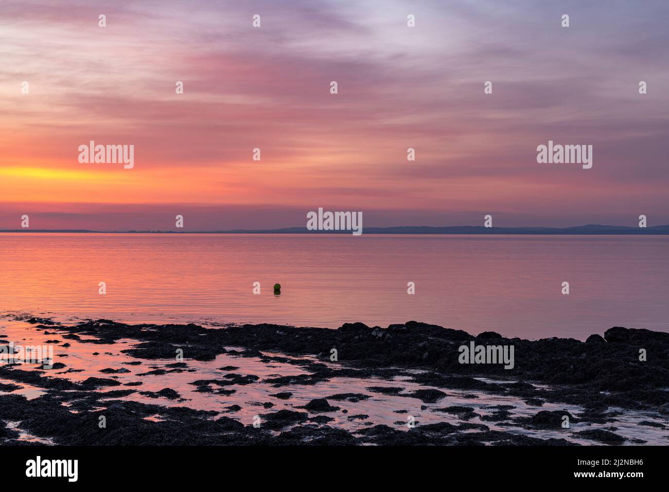Un leggero bagliore di pinkish che si riflette su un mare calmo Foto Stock