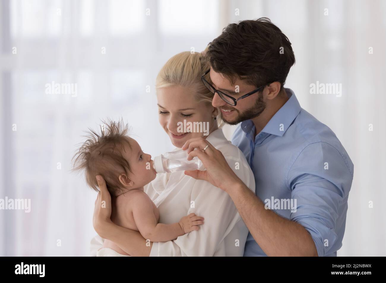 Mamma e papà giovani felici che si prendono cura del bambino carino insieme Foto Stock