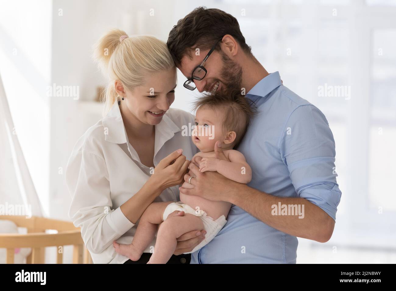 Allegro felice coppia di giovani genitori coccolare adorabile bambino Foto Stock