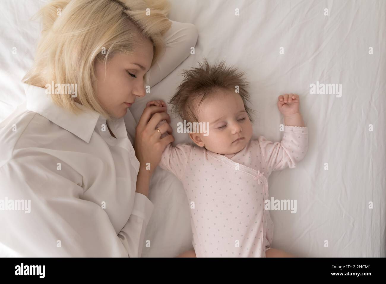 Mamma e bambina bionda stanchi dormono insieme Foto Stock