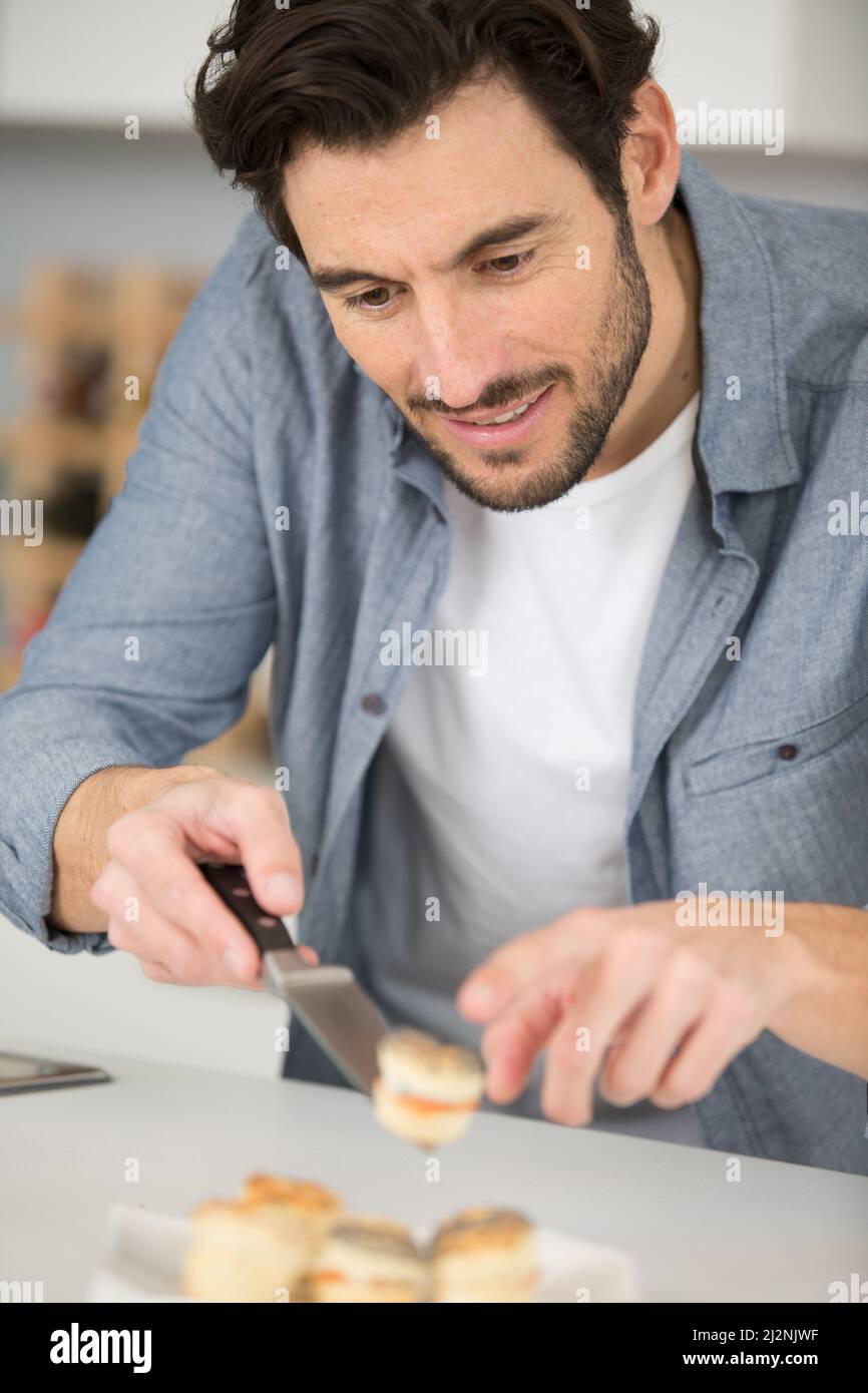 uomo che prepara tapas per i visitatori a casa Foto Stock