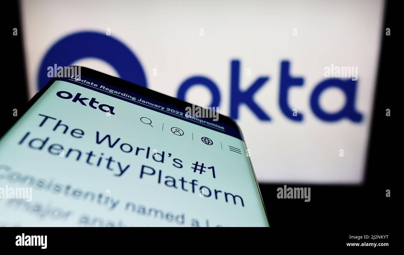 Telefono cellulare con sito web della società di gestione delle identità americana Okta Inc. Sullo schermo di fronte al logo aziendale. Mettere a fuoco sulla parte superiore sinistra del display del telefono. Foto Stock