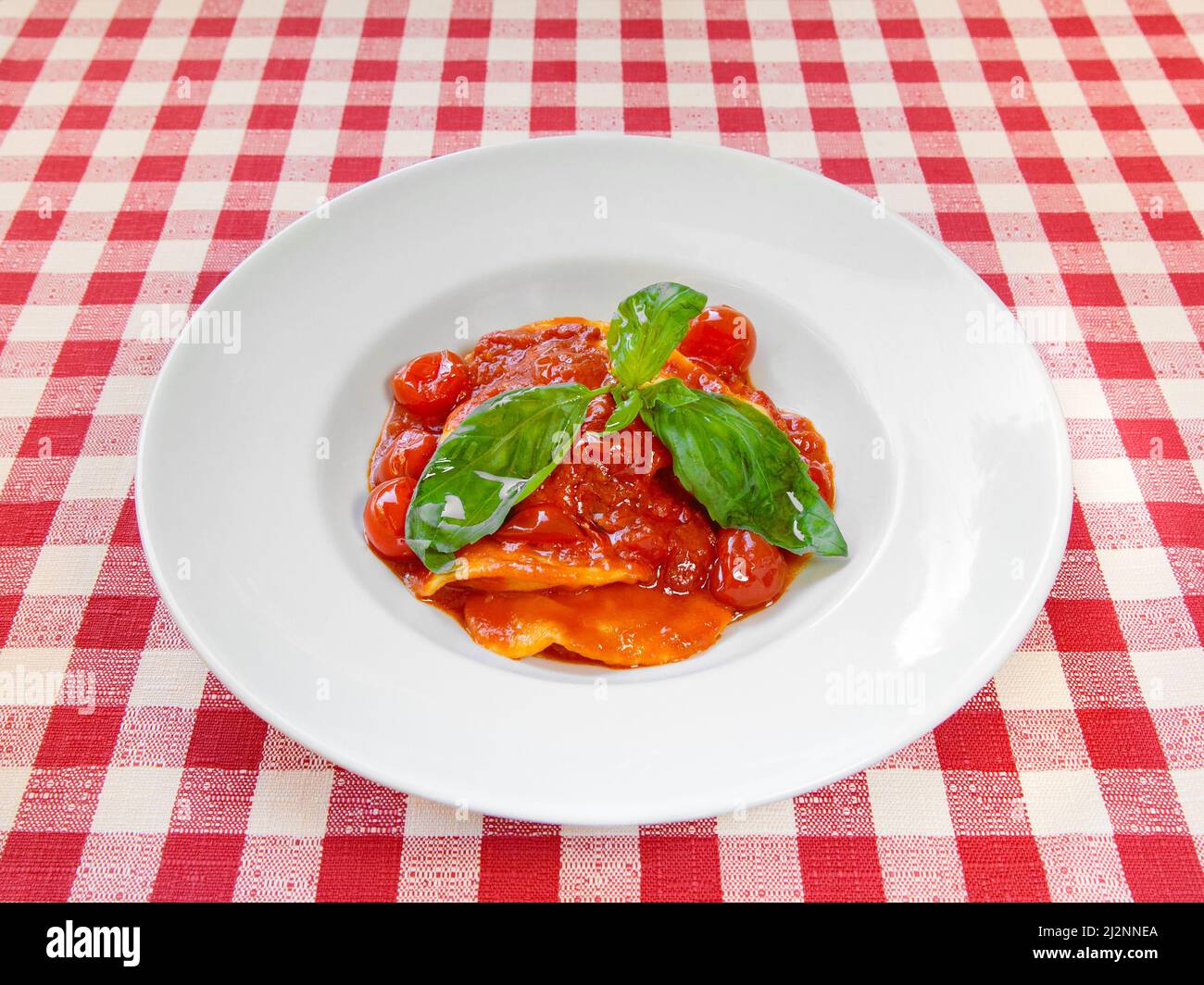 Piatto di ravioli con salsa di pomodoro fresco e basilico su tovaglia Foto Stock