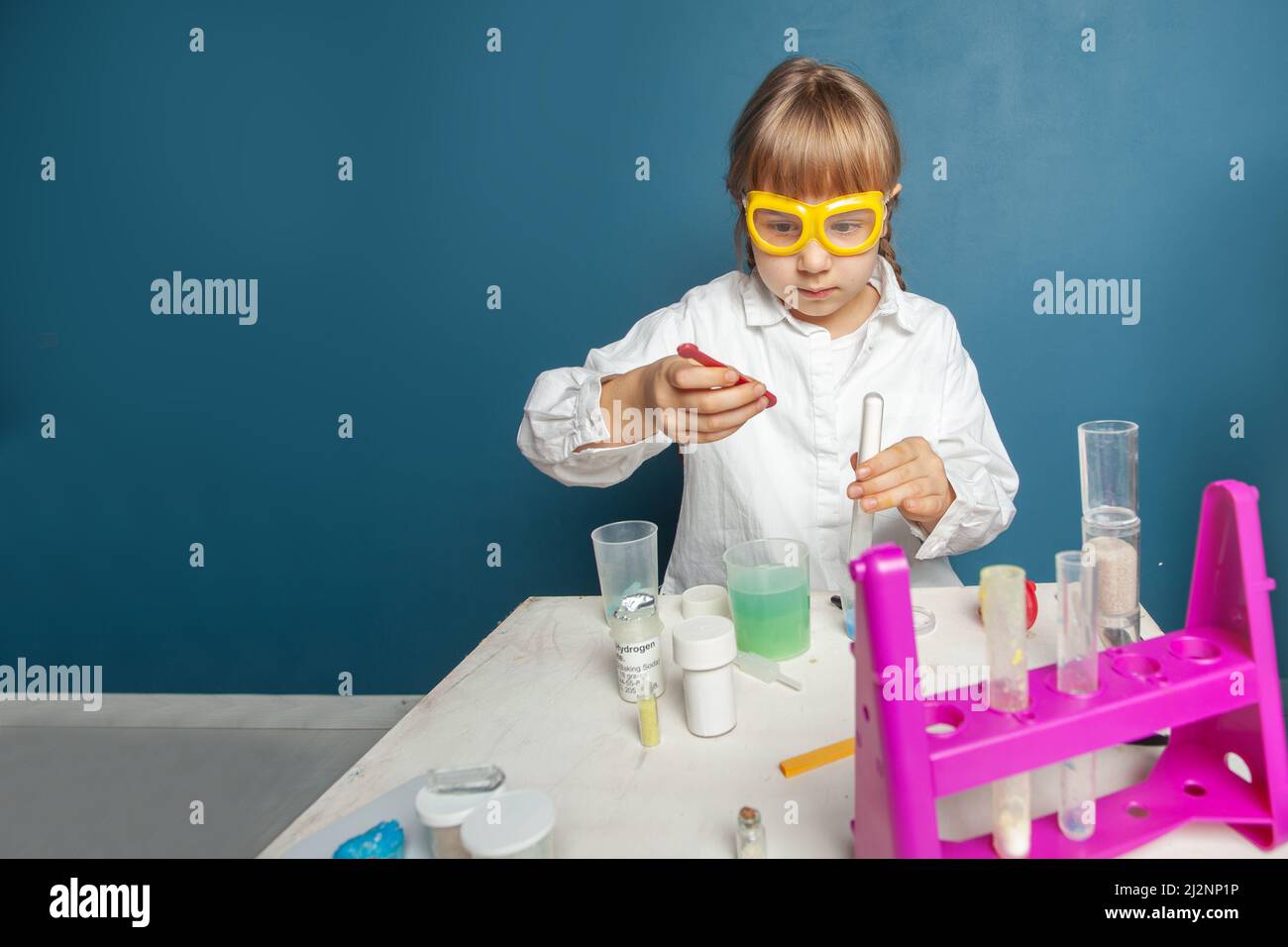 Studente ragazza intelligente imparare, fare un esperimento chimico e tenere provetta in mano in classe scientifica. Concetto di istruzione e scienza Foto Stock