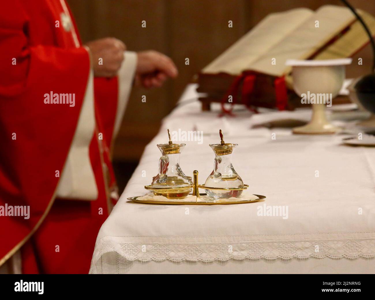 piccole ampolle di vetro durante la celebrazione della santa messa e il sacerdote che legge la santa bibbia Foto Stock