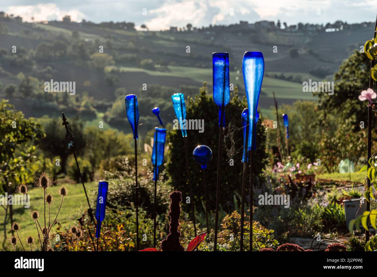 bottiglie di vetro blu come decorazione del giardino al tramonto Foto Stock