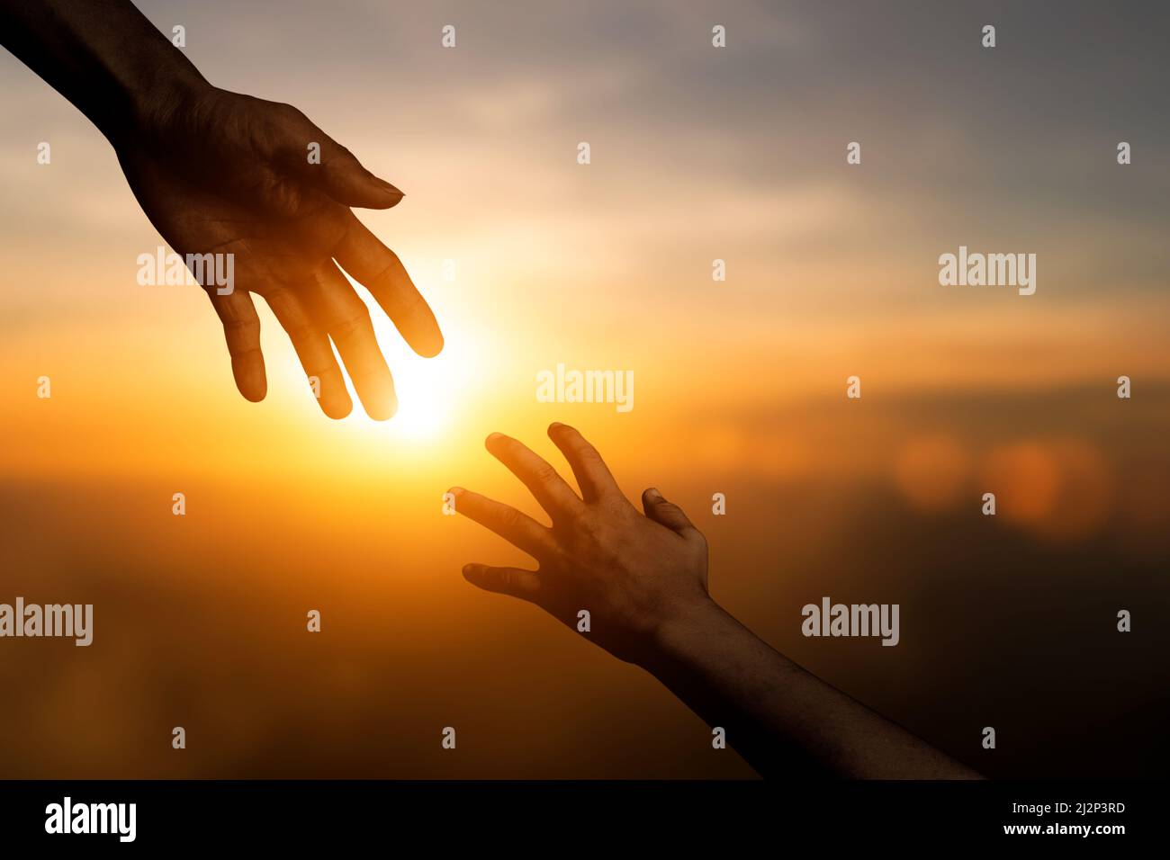 Silhouette di raggiungere, dare una mano, speranza e sostenere l'un l'altro su sfondo cielo sfocato tramonto. Concetto di giornata internazionale di pace e. Foto Stock
